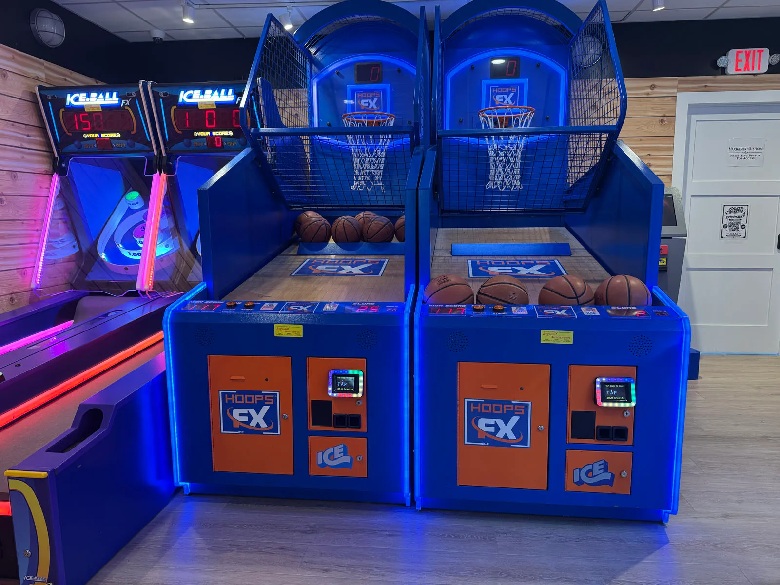 Basketball hoop games beside blue-lit skee-ball lanes