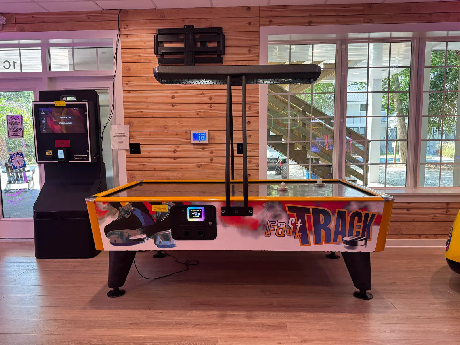 A Fast Track air hockey table by bright windows looking out to greenery