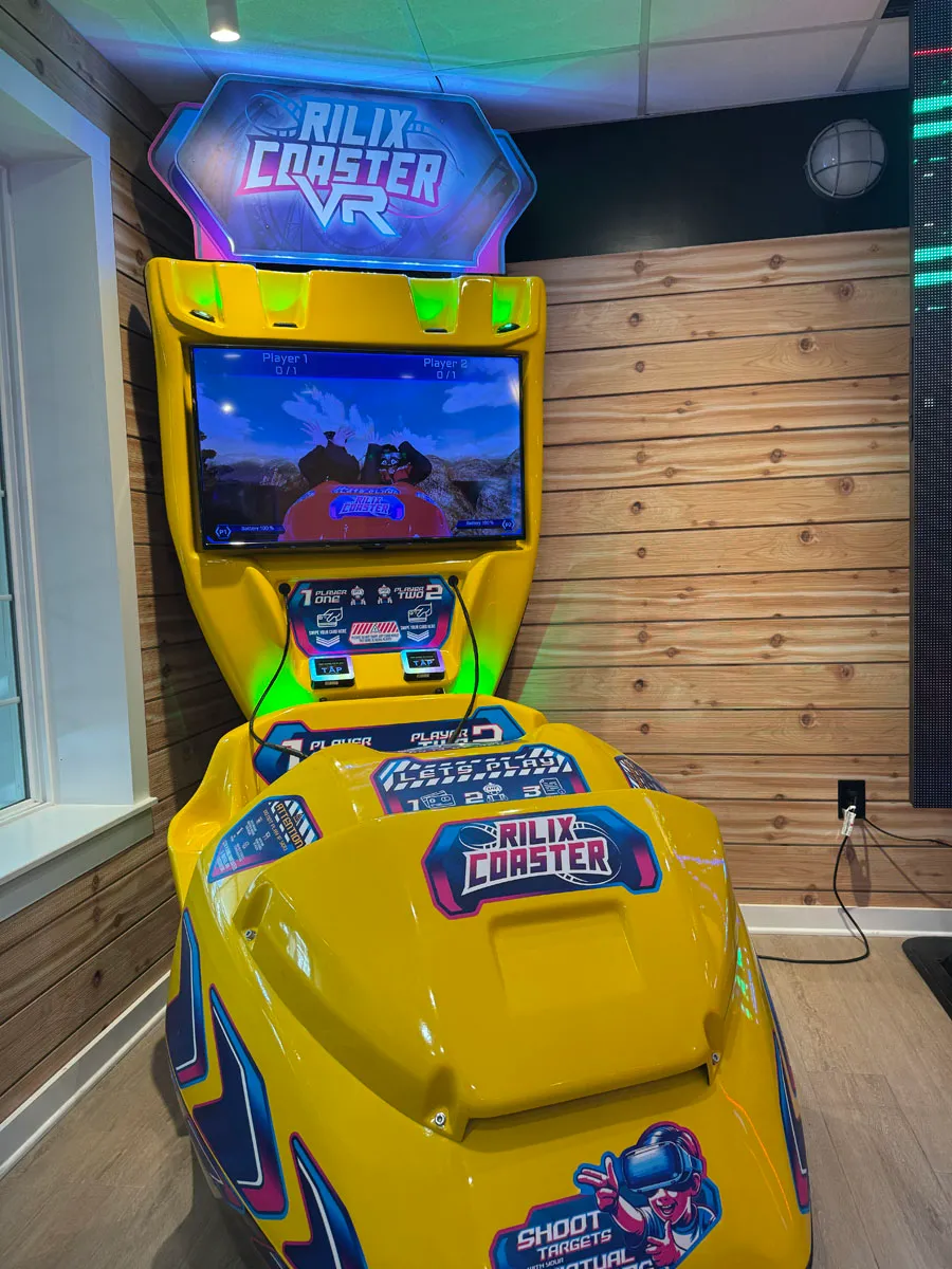 A tall virtual roller-coaster arcade cabinet against a wood-plank wall