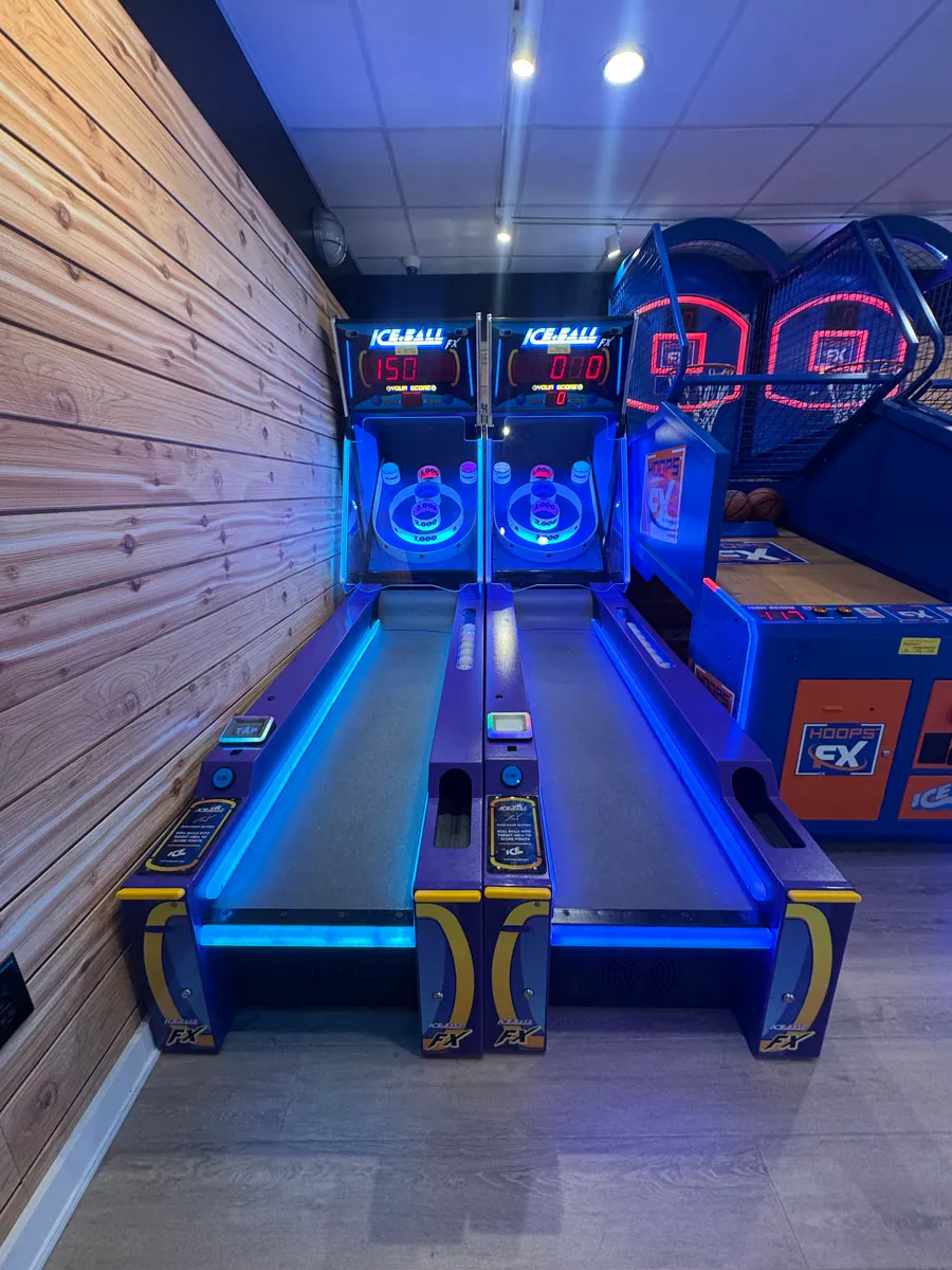 Two blue-lit skee-ball lanes viewed head-on