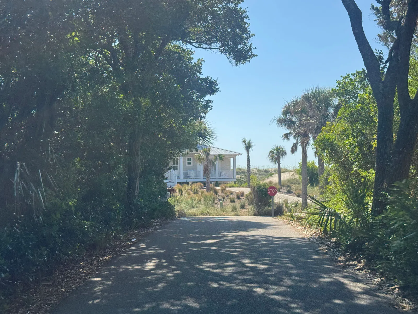 Path opening toward dunes and beach cottage with stop sign