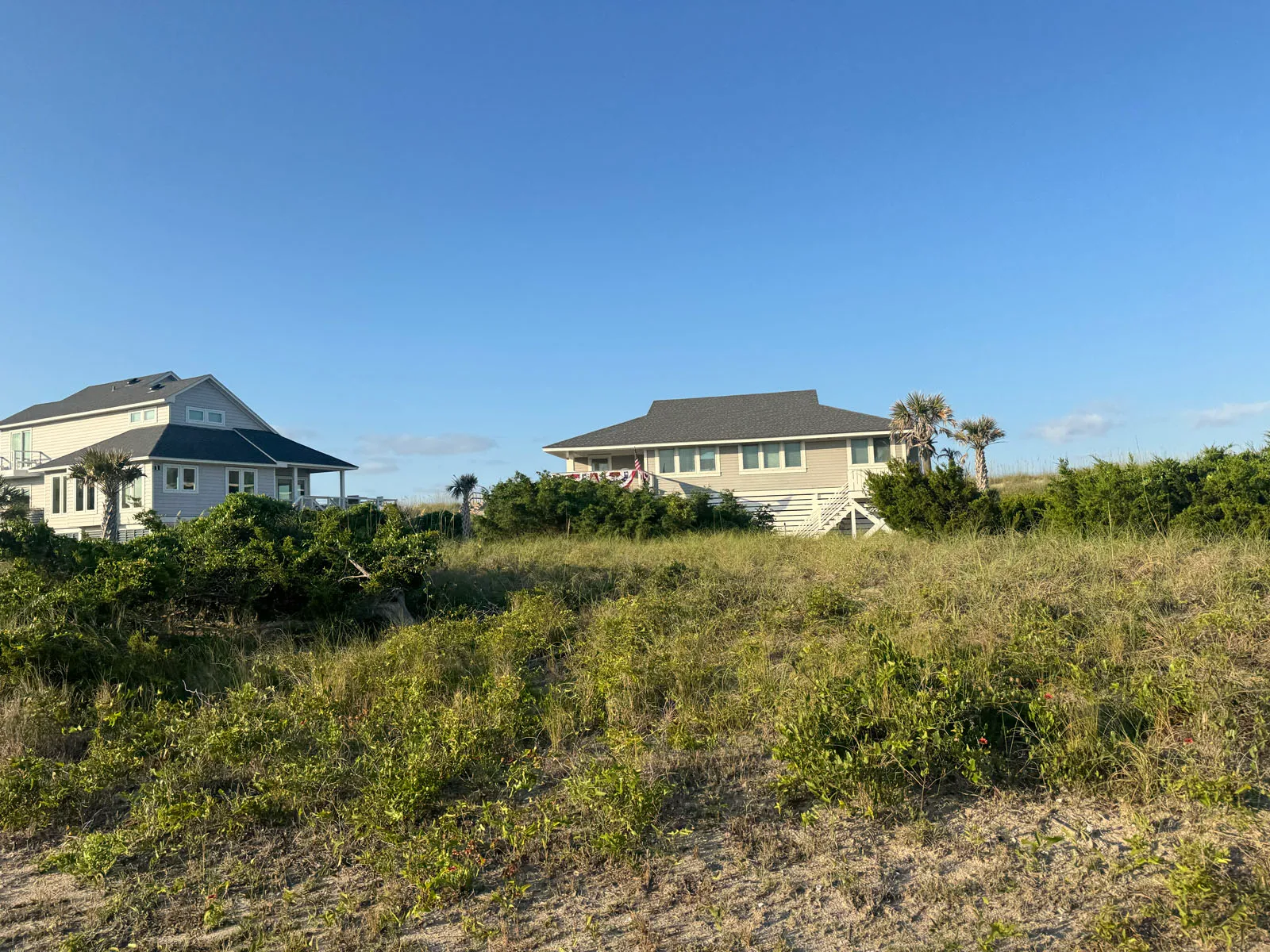 Two dune-top beach houses beyond scrub and sea grass