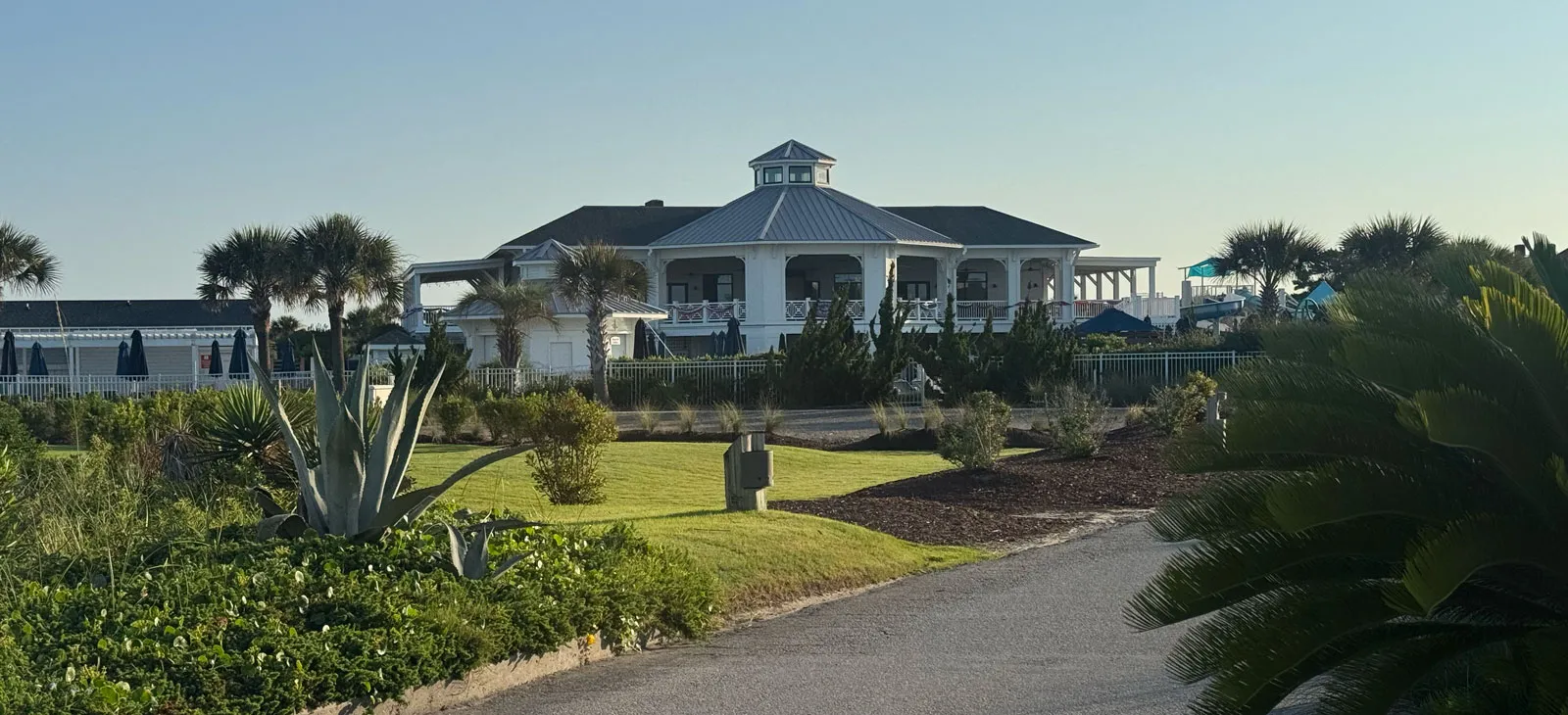 The Bald Head Island Club clubhouse behind a manicured lawn and palms