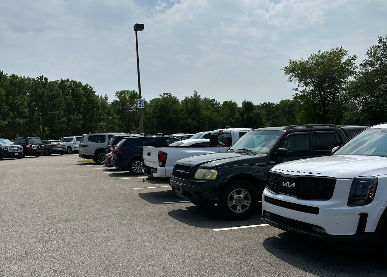 Rows of parked cars in the Deep Point Marina lot beside a row marker sign reading B2