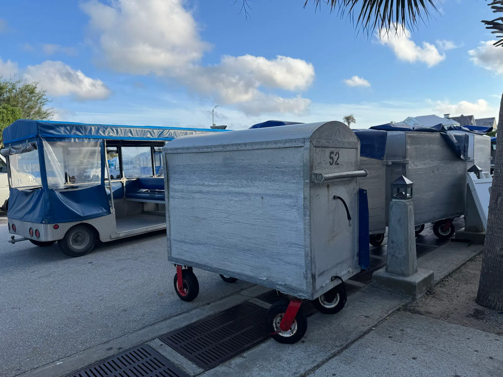 Aluminum luggage tram carts and blue passenger tram at dock
