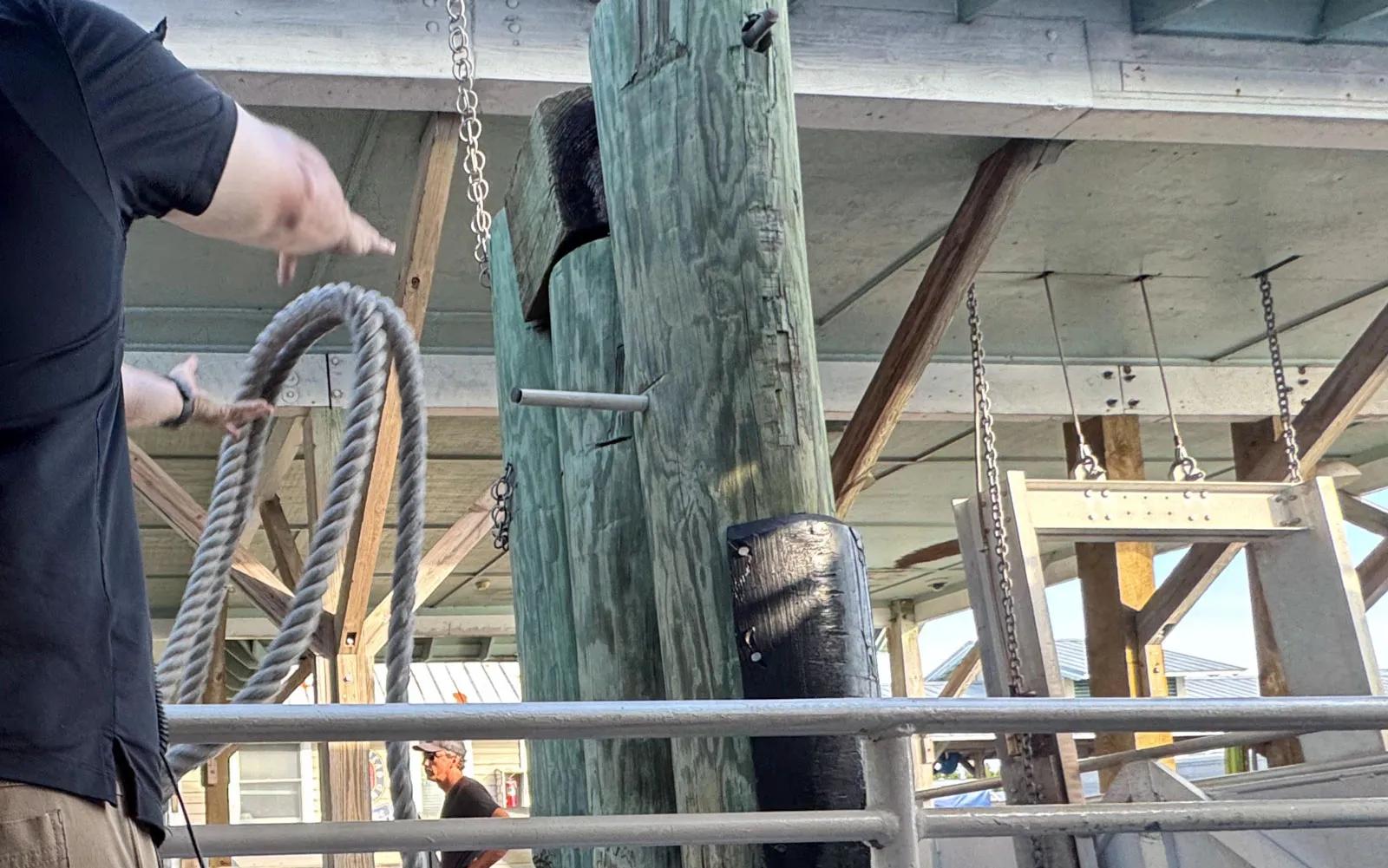 A marina deckhand coiling a heavy dock line under the ferry pier