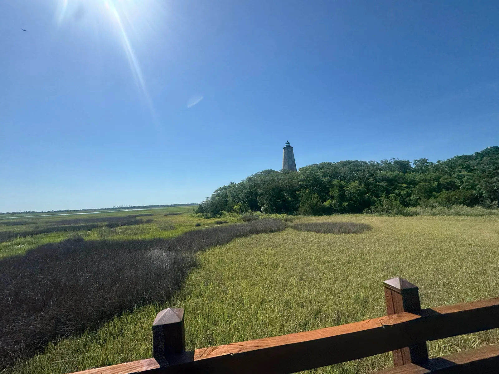 Old Baldy lighthouse rising above marsh grass and treeline