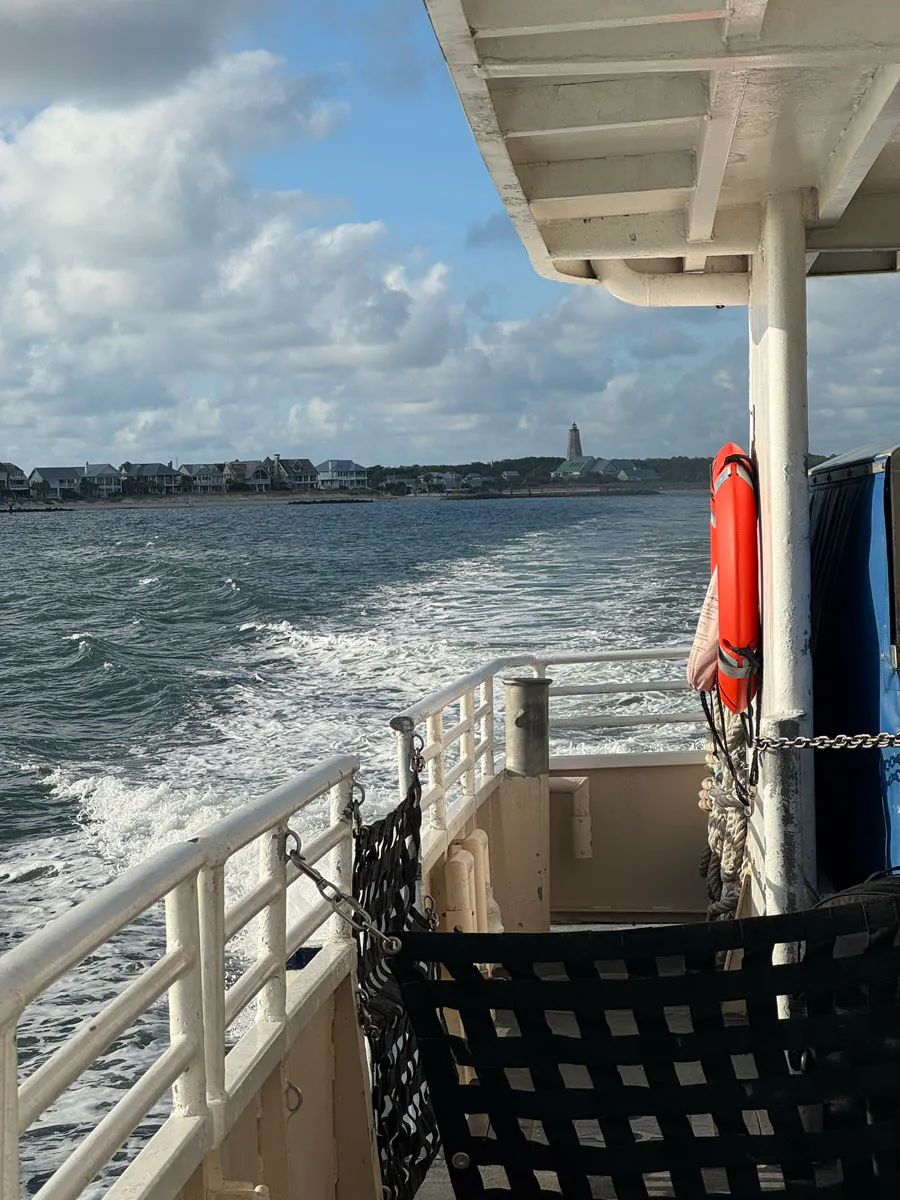 Old Baldy lighthouse framed by the ferry railing and a life ring, seen from aboard