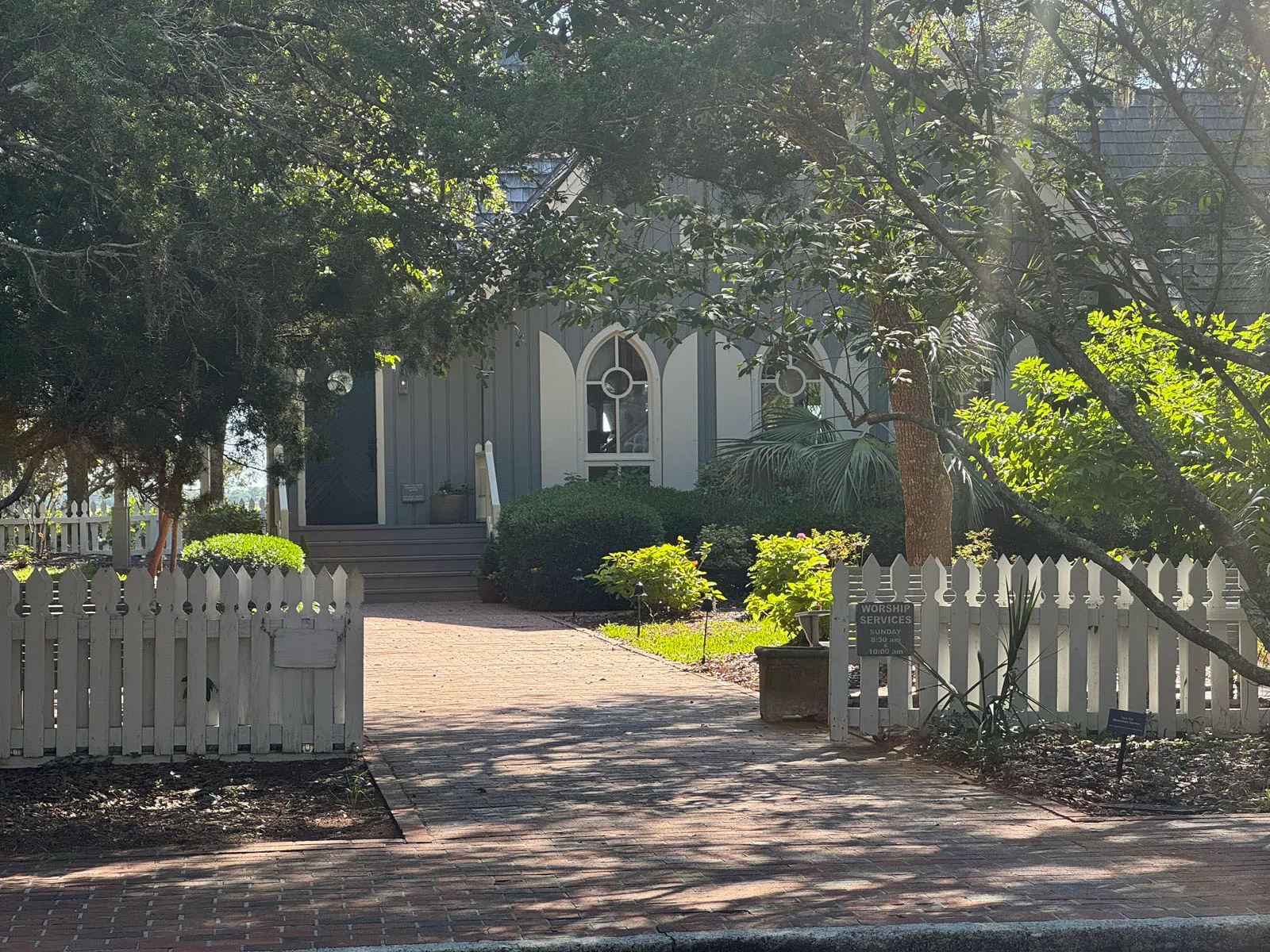 Village Chapel with arched window behind picket fence and marker