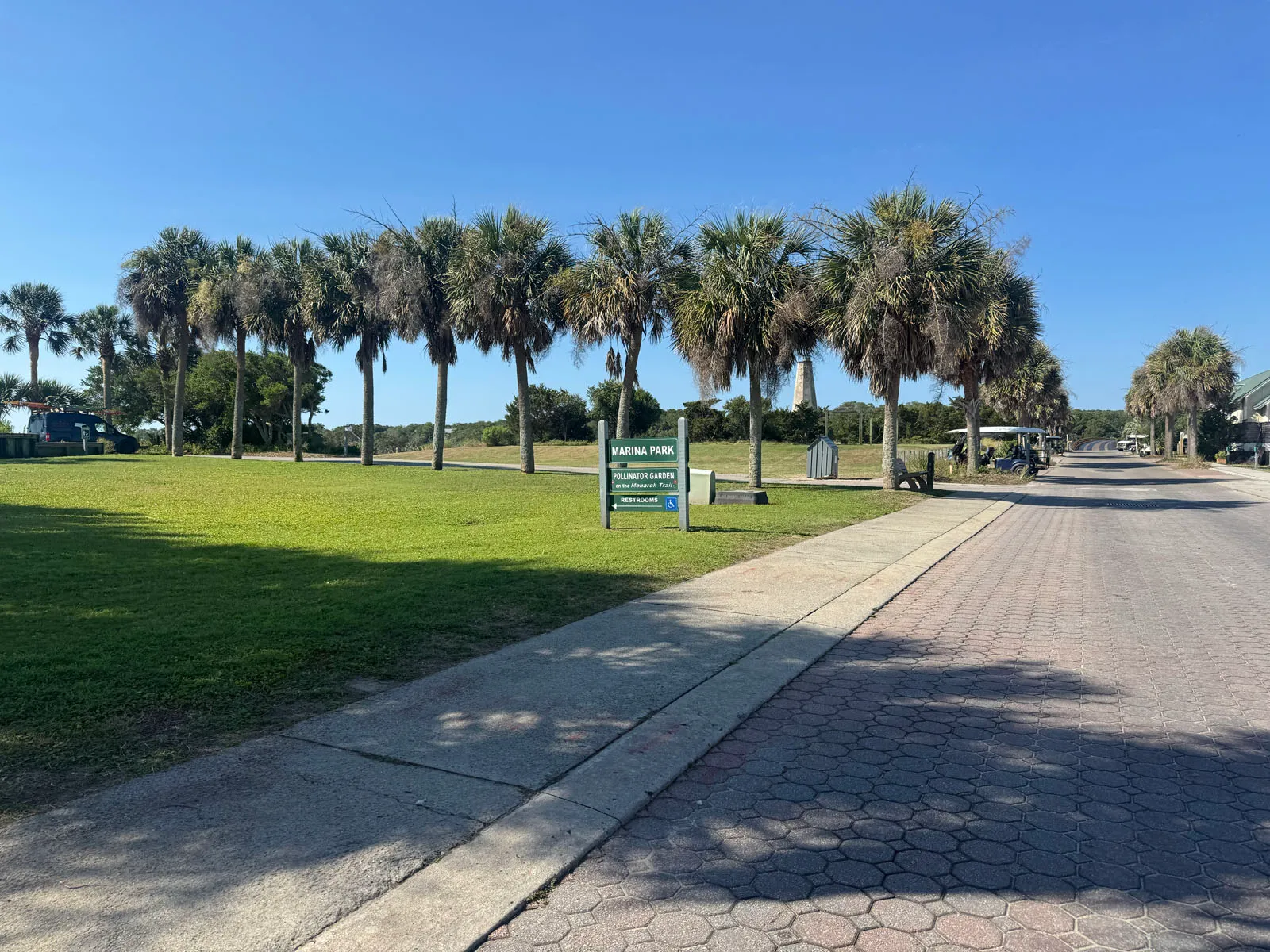 Palm-lined Marina Park lawn with paver walk and lighthouse distant