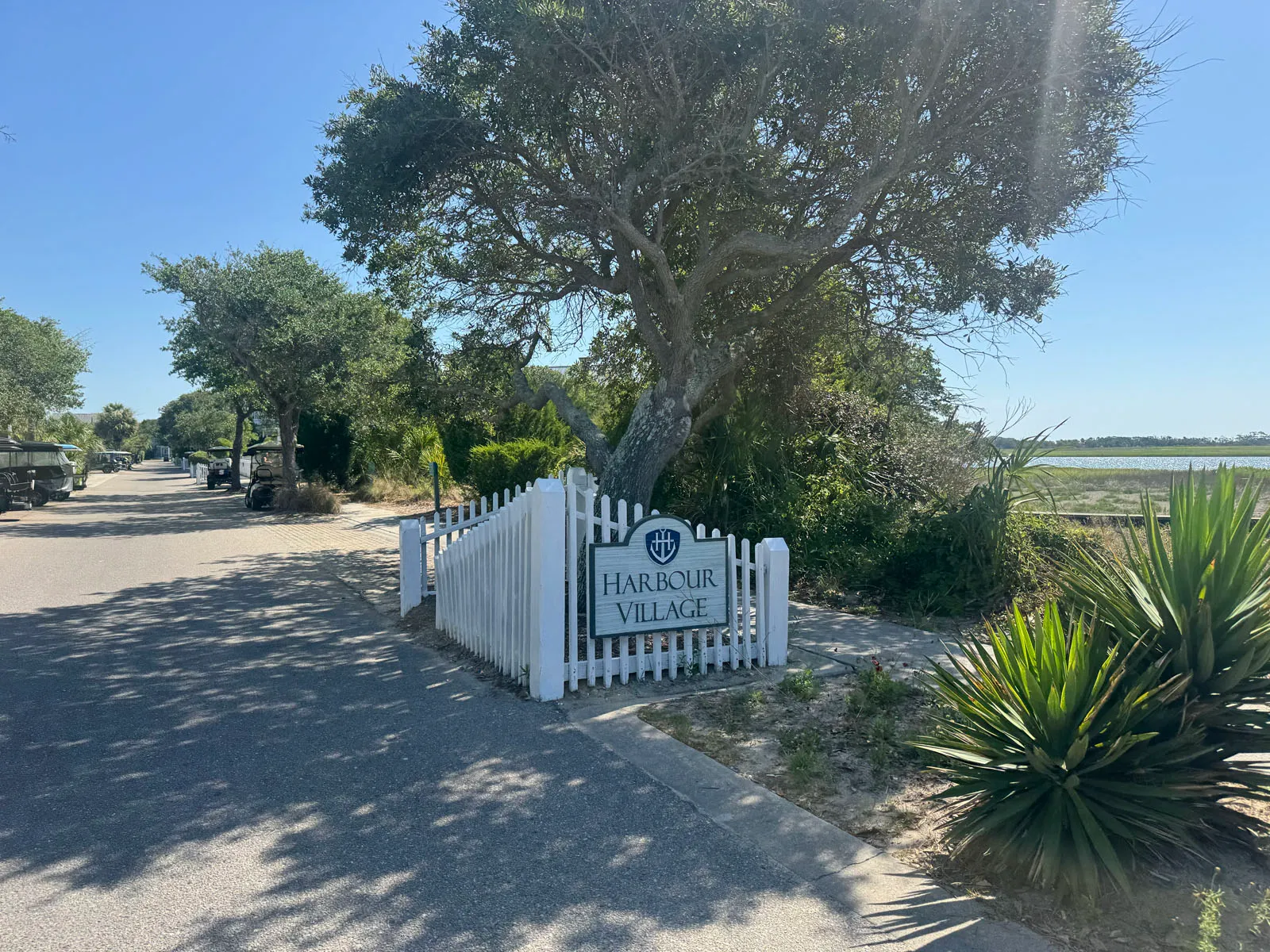 Harbour Village entrance sign with oak, marsh, and golf carts